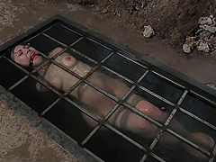 Bondage scene with brunette slut in a water prison