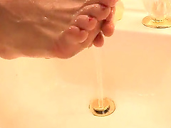 Horny blonde chick plays with her feet in the bathroom. HD video