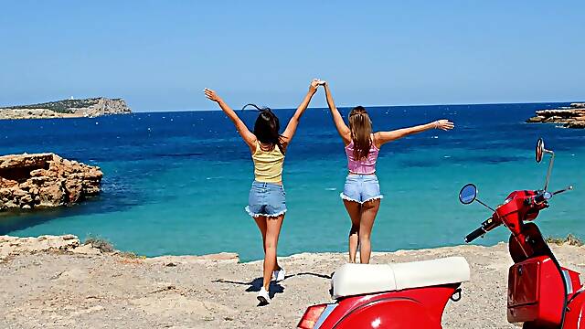 Two beautiful girls have fun on the beach with a guy, showcasing sensual moves.